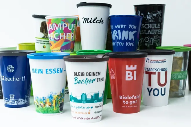 Anordnung vieler to go-Becher in den individuellen Designs der verschiedenen Partner und Projekte von ORNAMIN